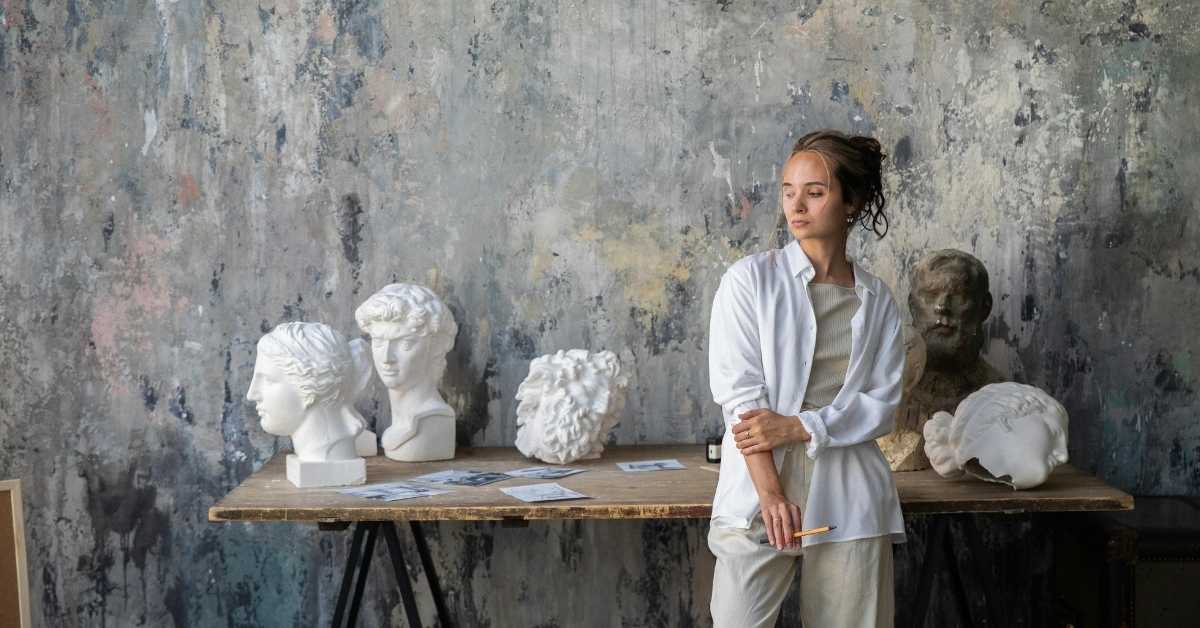 young woman standing by table with plaster busts and papers