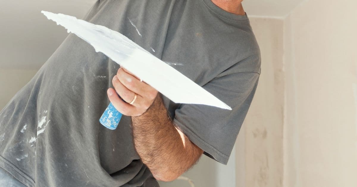 Man holding plastering hawk with fresh white plaster
