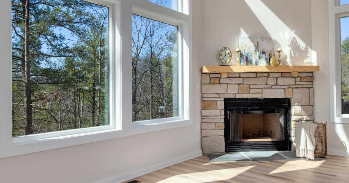 Indoor stone fireplace with mantel and large windows
