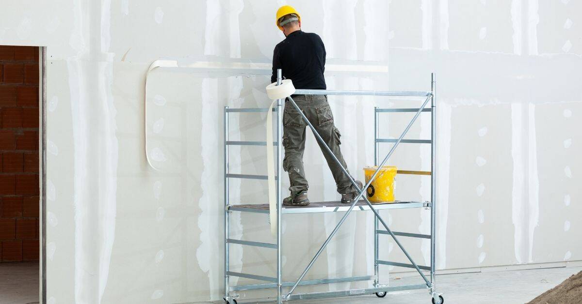 Worker in yellow helmet standing on metal scaffolding