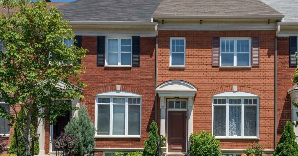 Red brick townhouse with windows and door under clear sky
