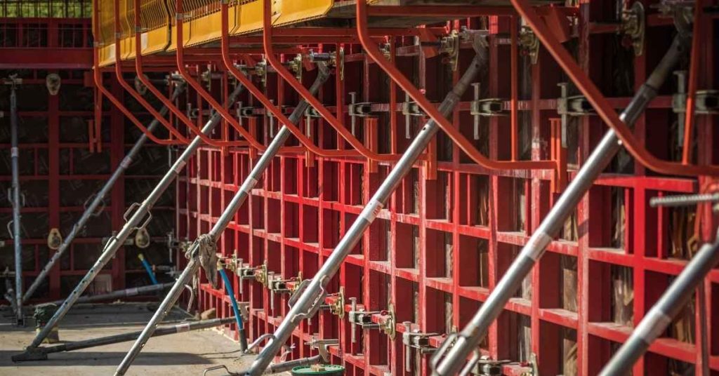 Red metal concrete formwork with angled braces and safety railing