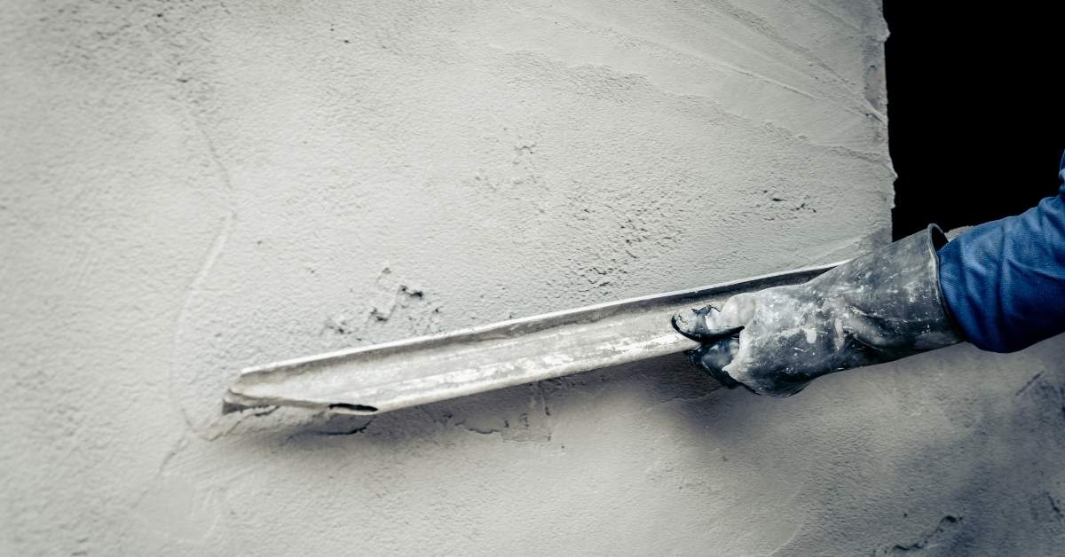 Hand with glove smoothing fresh stucco on wall