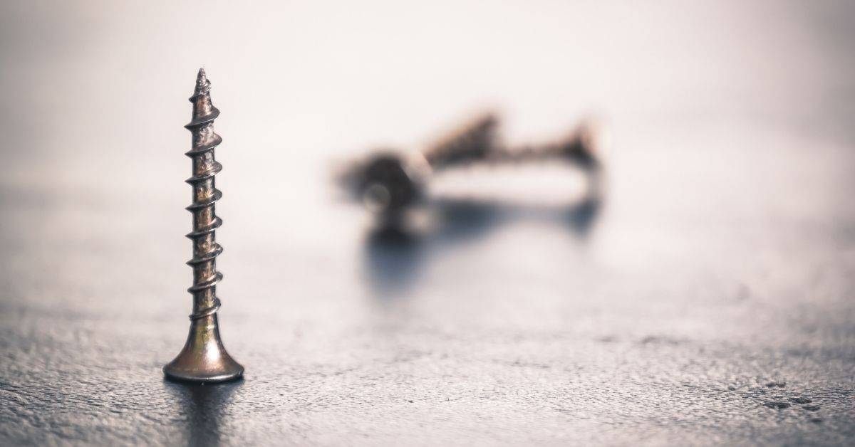 Closeup of metal screws standing on textured surface