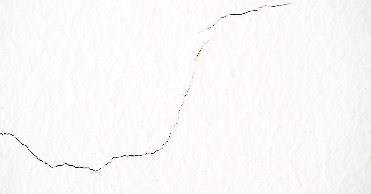 Close-up of cracked white stucco wall surface
