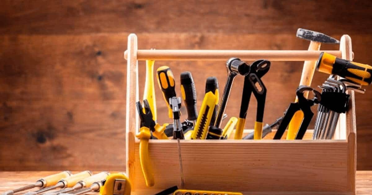 Wooden toolbox with various hand tools on wood background