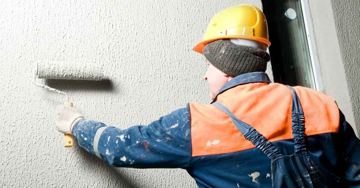 Construction worker applying textured stucco with roller