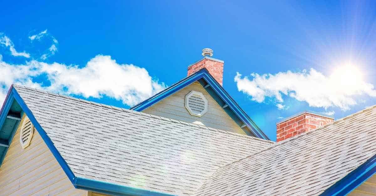asphalt shingle roof with brick chimneys under blue sky