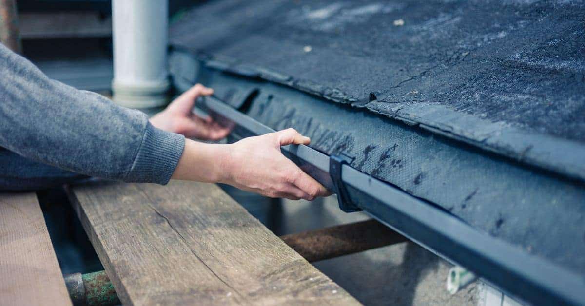 Hands installing or inspecting a metal roof gutter