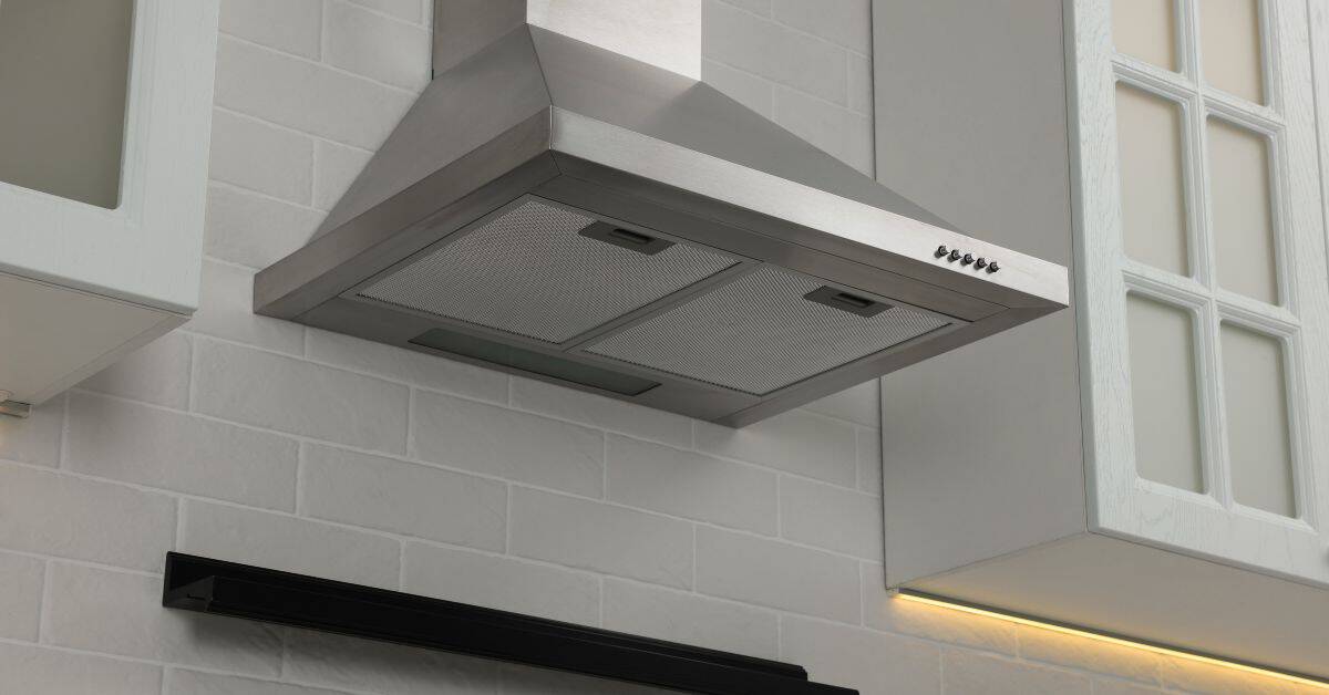 stainless steel kitchen vent hood mounted on tiled wall