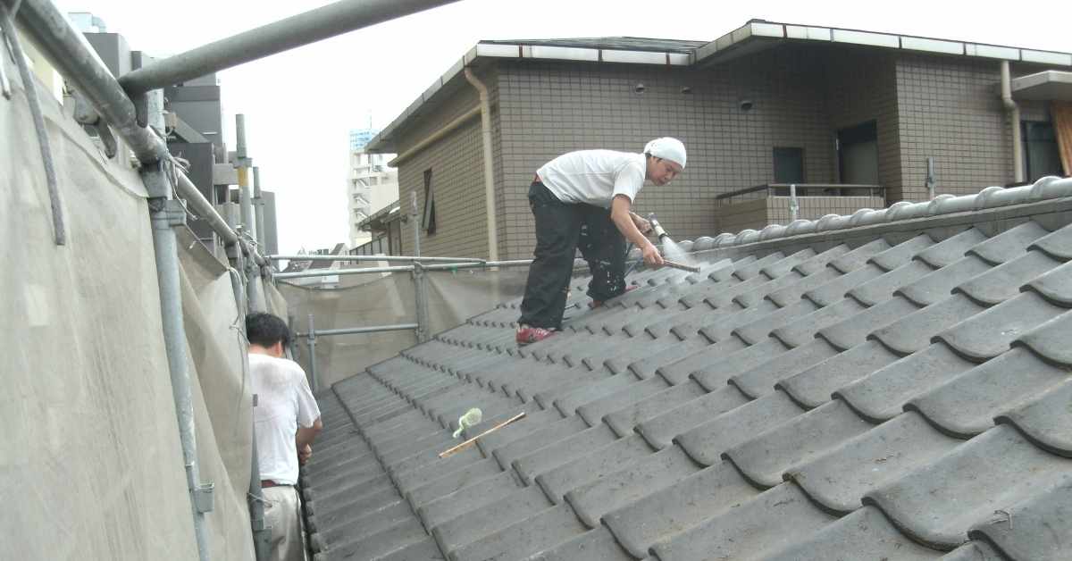 Two workers cleaning tiled roof under construction