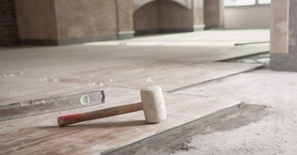 Rubber mallet and level on concrete floor with tiles