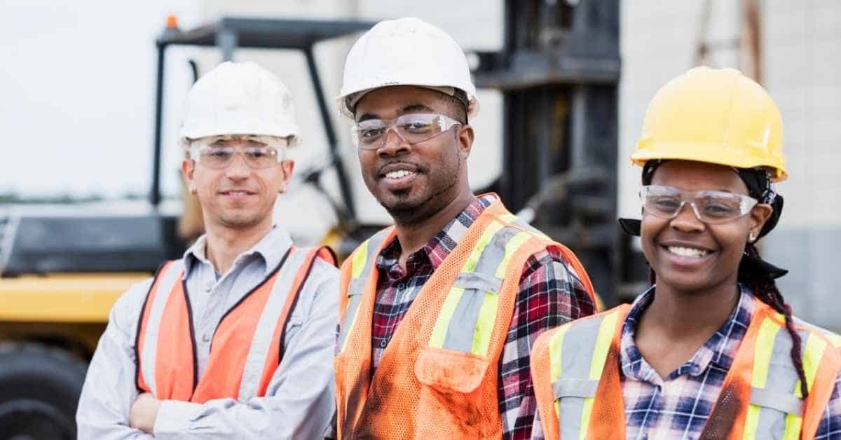 Three construction workers wearing safety helmets and vests