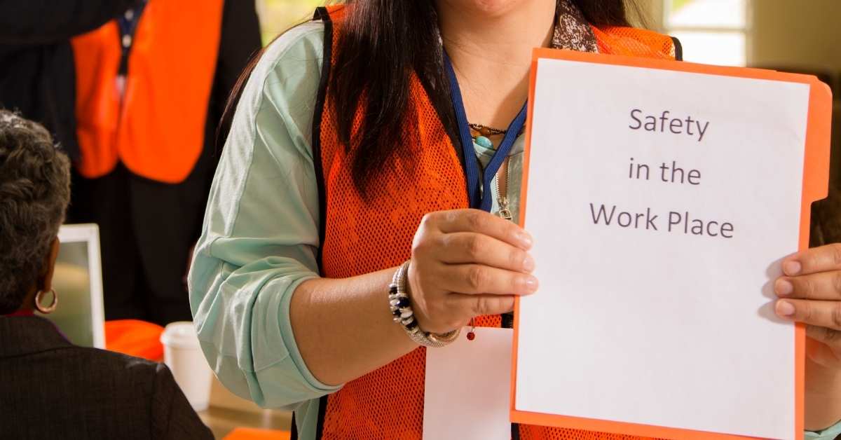 Person holding safety document titled Safety in the Work Place