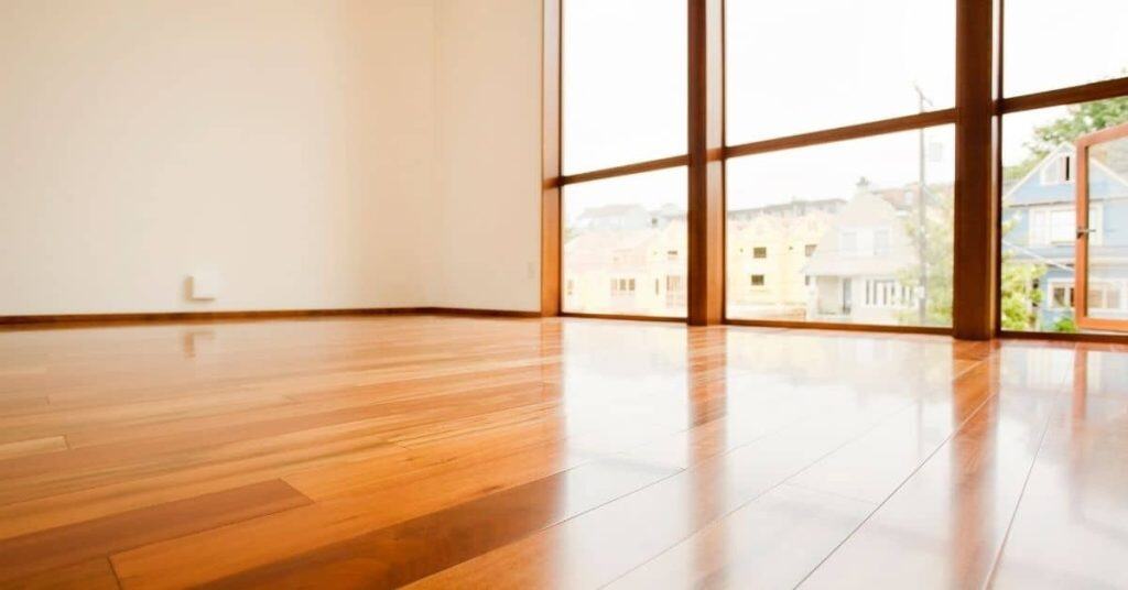 Shiny polished hardwood floor with large window reflection