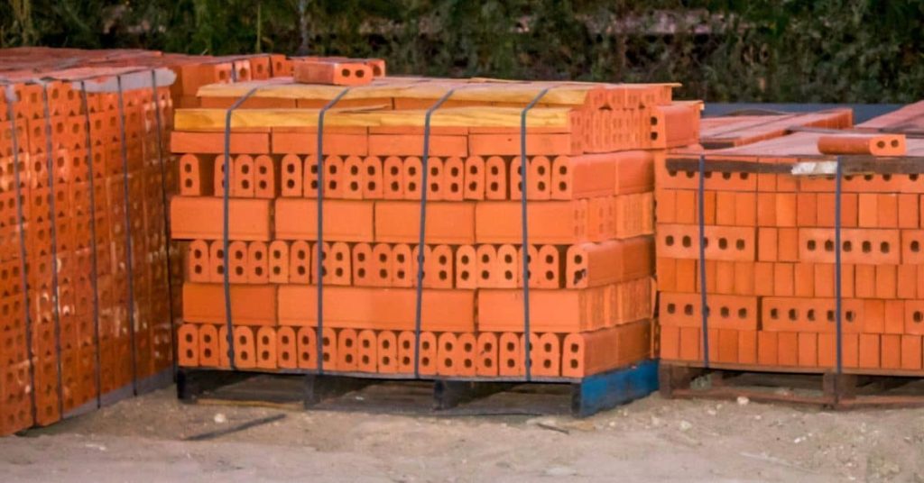 Stacks of orange hollow clay bricks on wooden pallets