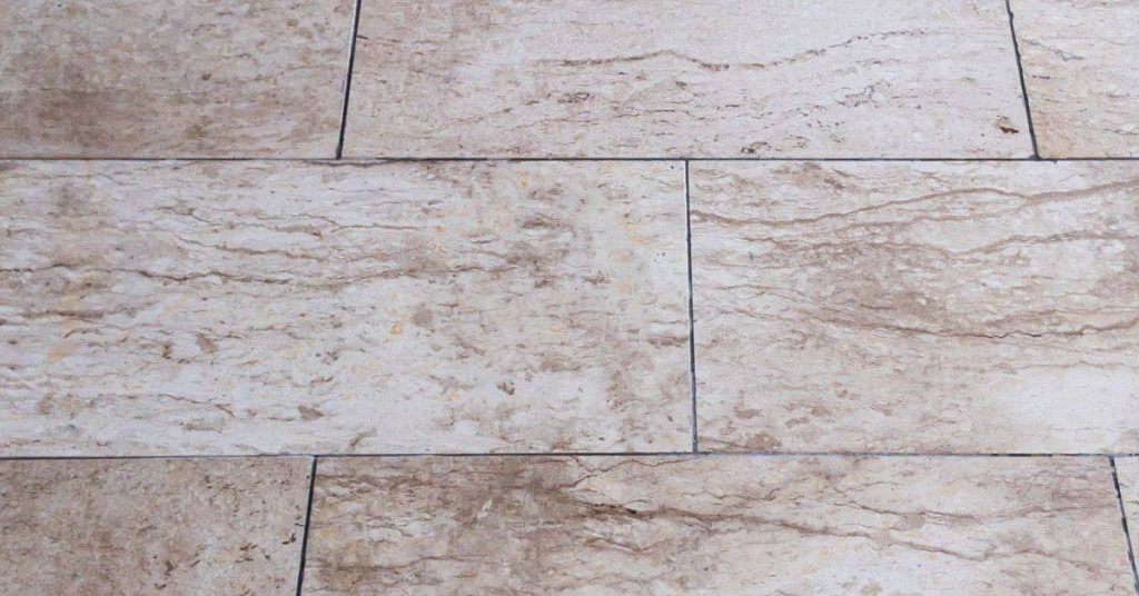 Textured beige stone tile floor with grout lines