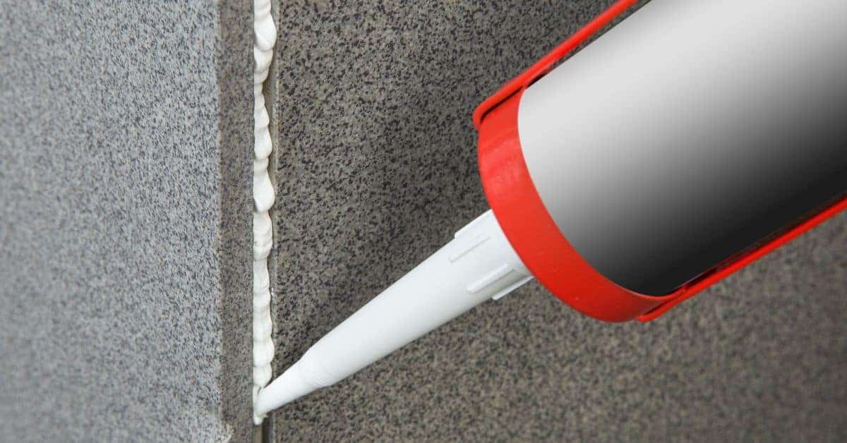 applying white expanding foam sealant to gap between wall surfaces