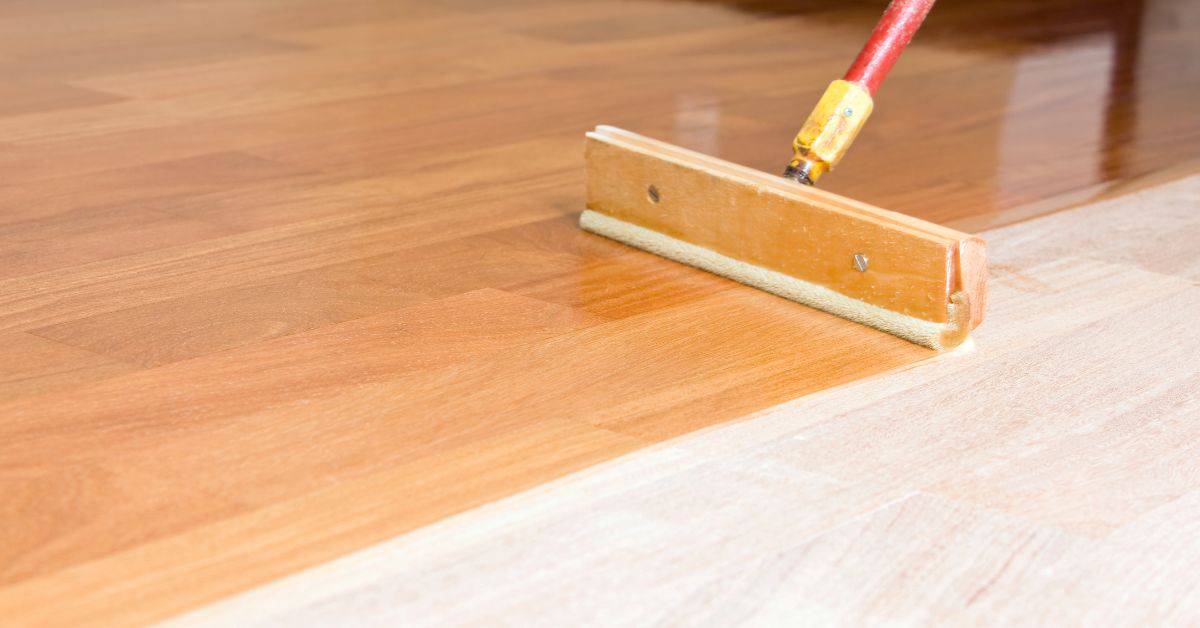 wood floor being finished with a wooden applicator tool