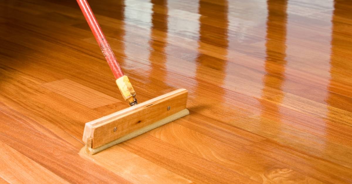 Wooden floor being polished with a long-handled mop