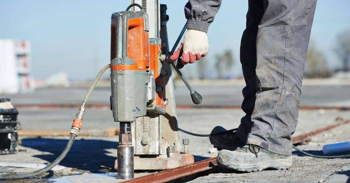 worker operating concrete core drilling machine on concrete surface