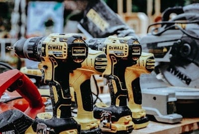 Three cordless DeWalt power drills on a wooden workbench