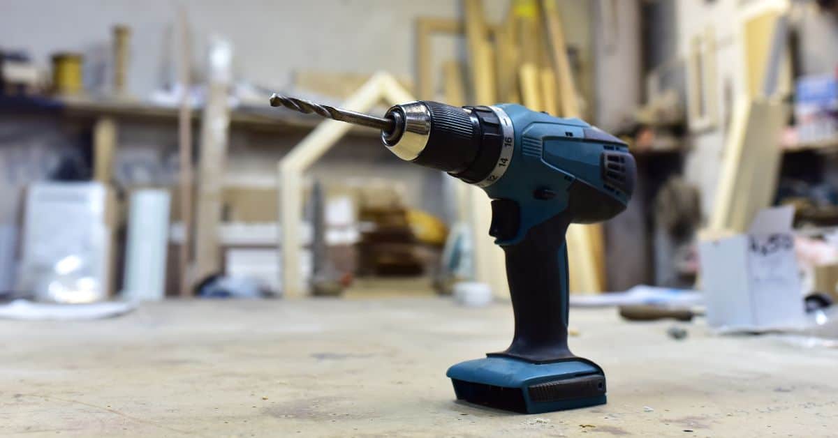 Cordless power drill with drill bit on workshop table