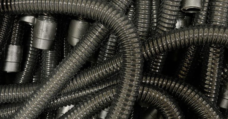 Close-up of black flexible industrial vacuum hoses piled together