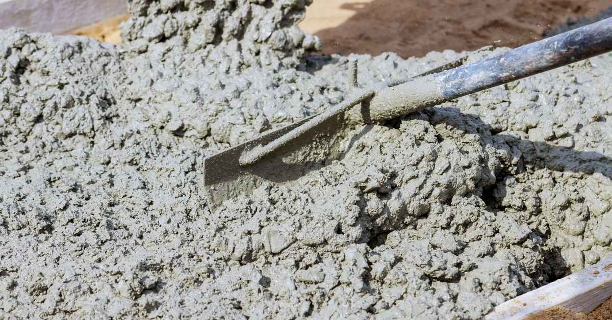 Shovel mixing fresh wet concrete in a container
