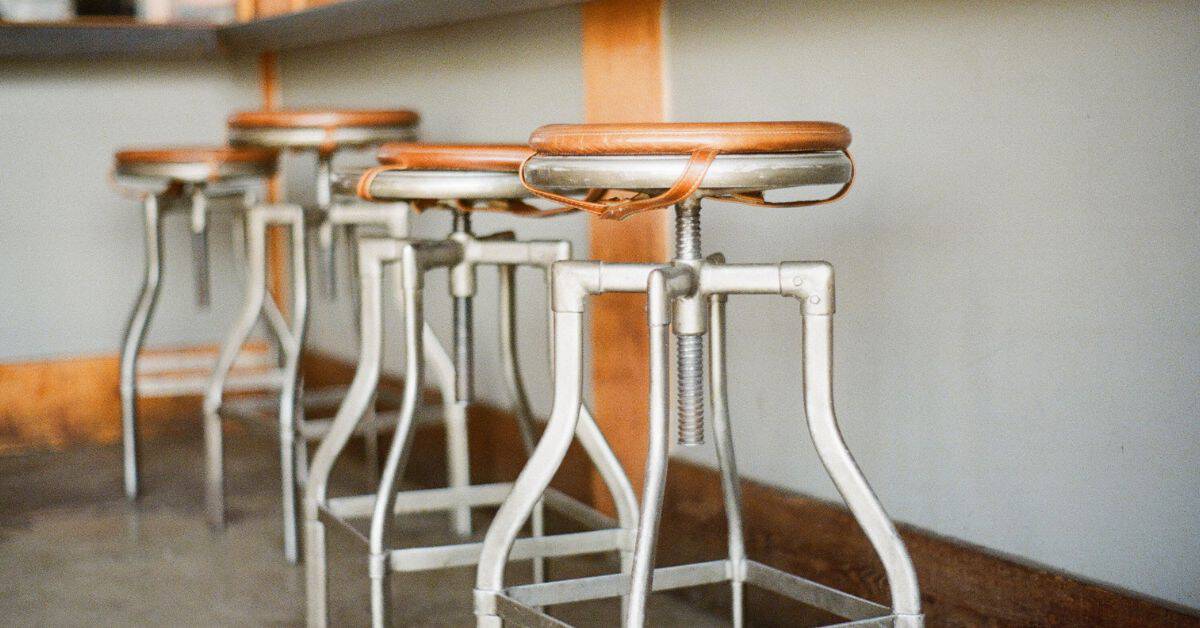 Row of metal bar stools with wooden seats