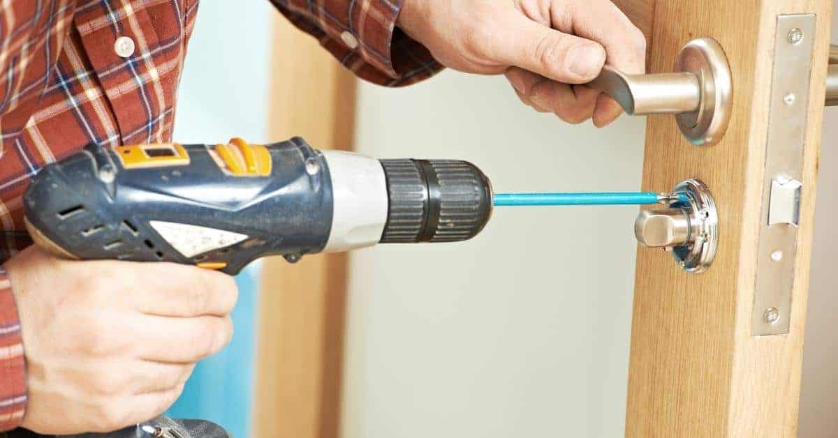 Person using power drill to remove door lock screws