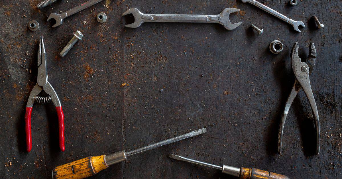 Various hand tools and metal fasteners on a rusty surface