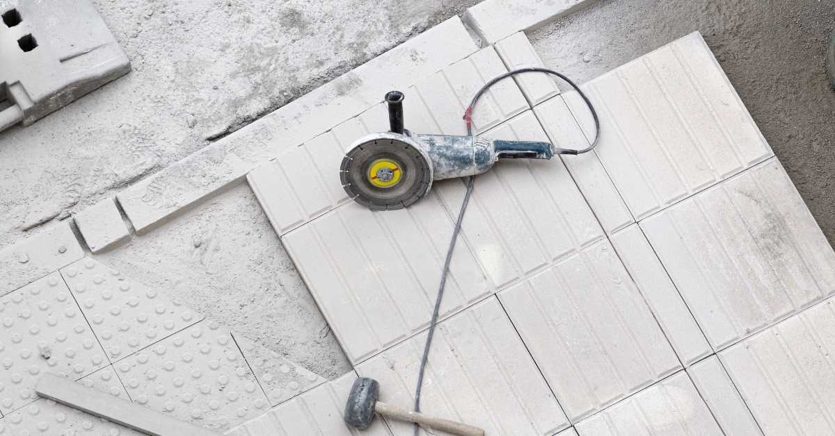 electric grinder hammer and rectangular floor tiles on dusty floor
