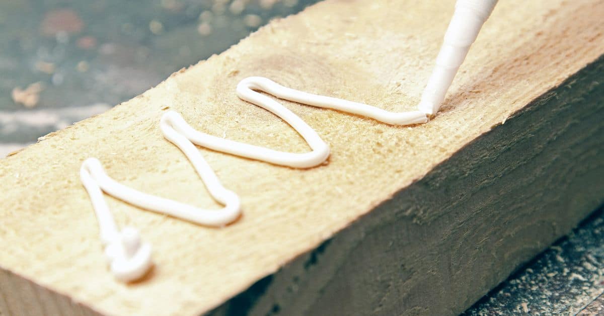 white wood glue being applied on rough lumber surface