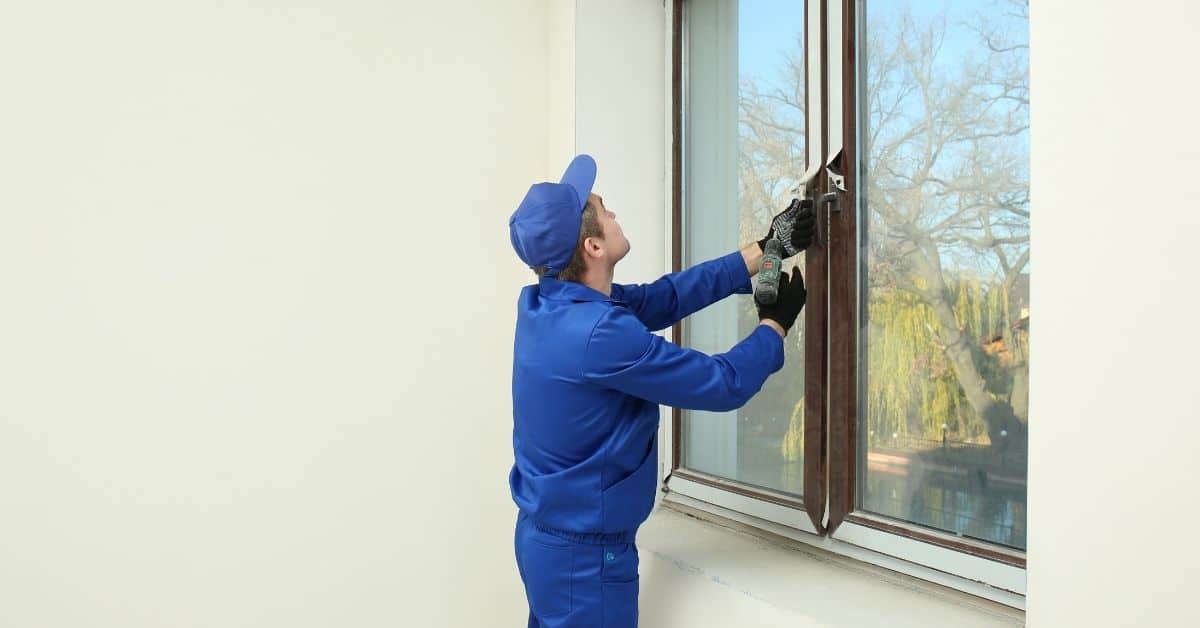 Worker in blue uniform installing window frame indoors