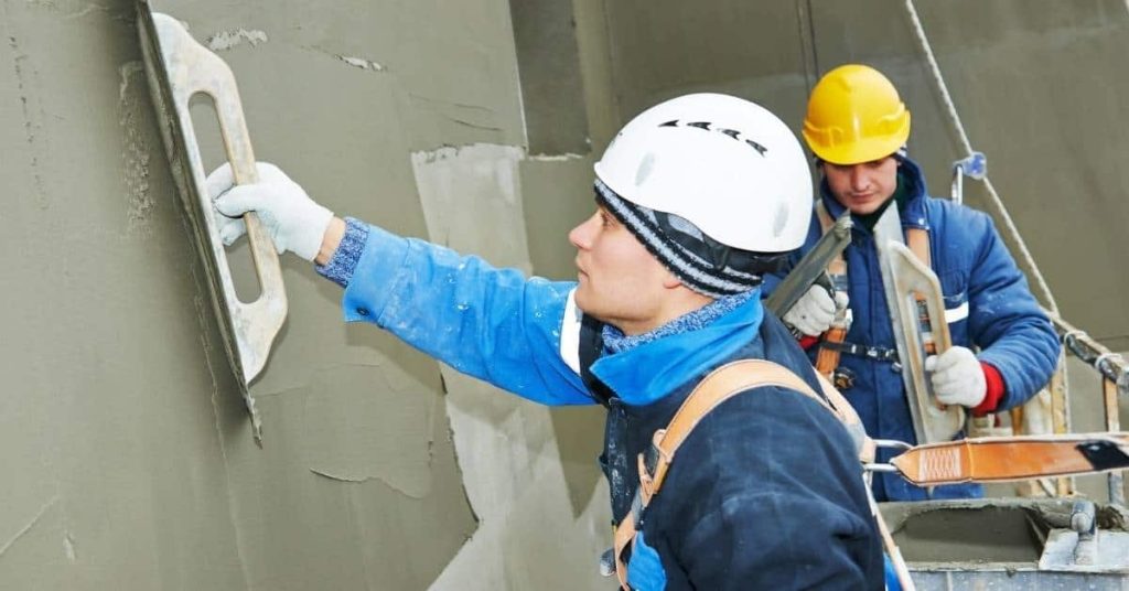 Two construction workers applying stucco to exterior wall