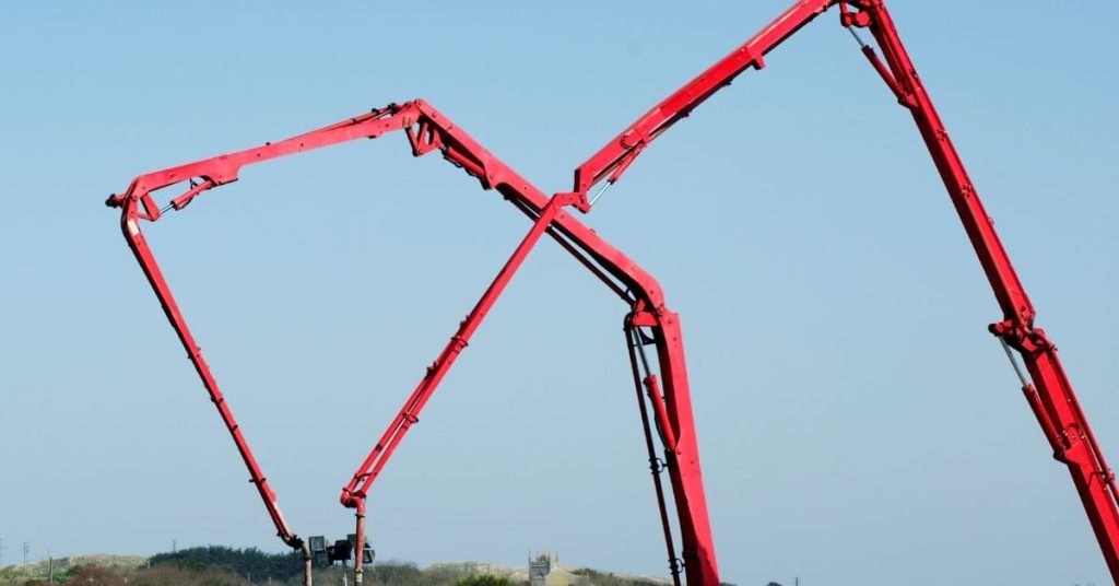 Two red concrete pump booms reaching upward
