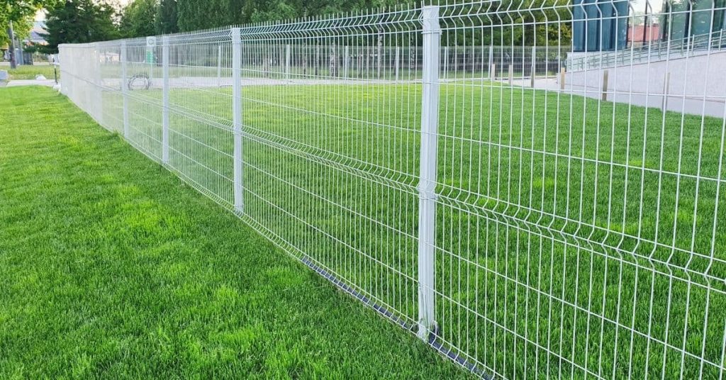 White galvanized metal wire fence on green grass
