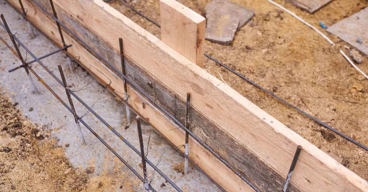 Wooden concrete form with steel rebar cage on dirt ground