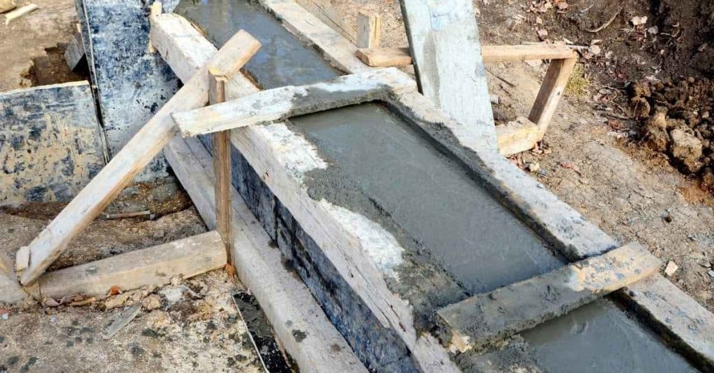 Wooden forms holding freshly poured concrete swale