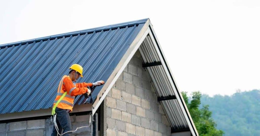 Worker installing metal roofing on building under construction