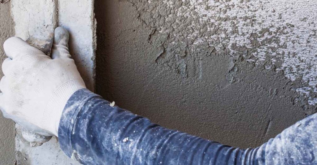 Worker smoothing plaster on a wall with a trowel