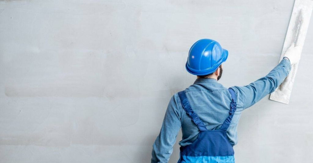 Worker smoothing stucco wall with float tool