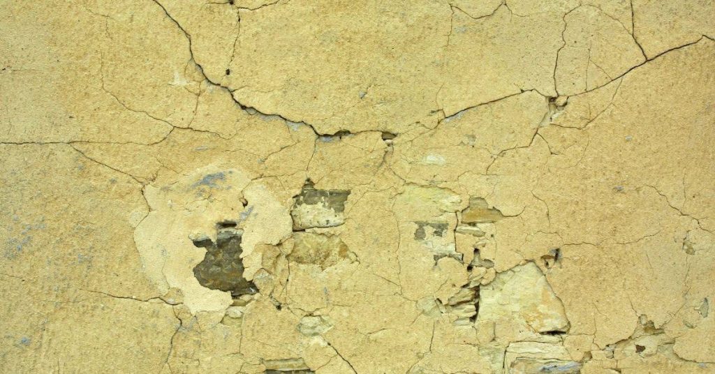 Yellow cracked and deteriorated concrete wall surface