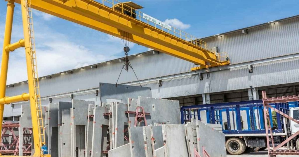Yellow crane lifting precast concrete panels outdoors