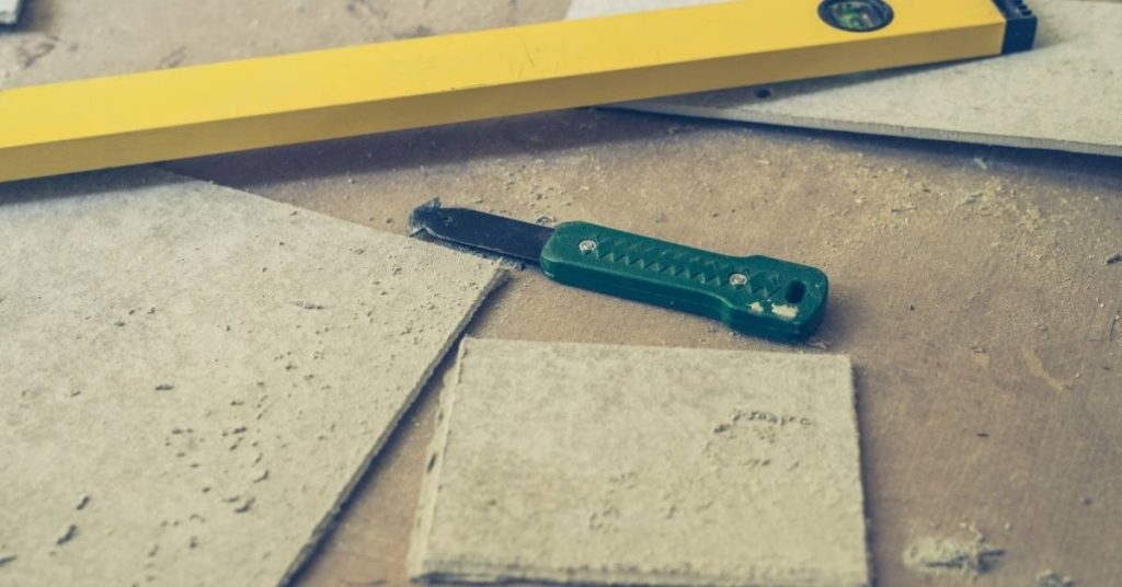Yellow level tool and green cutting knife on concrete board pieces