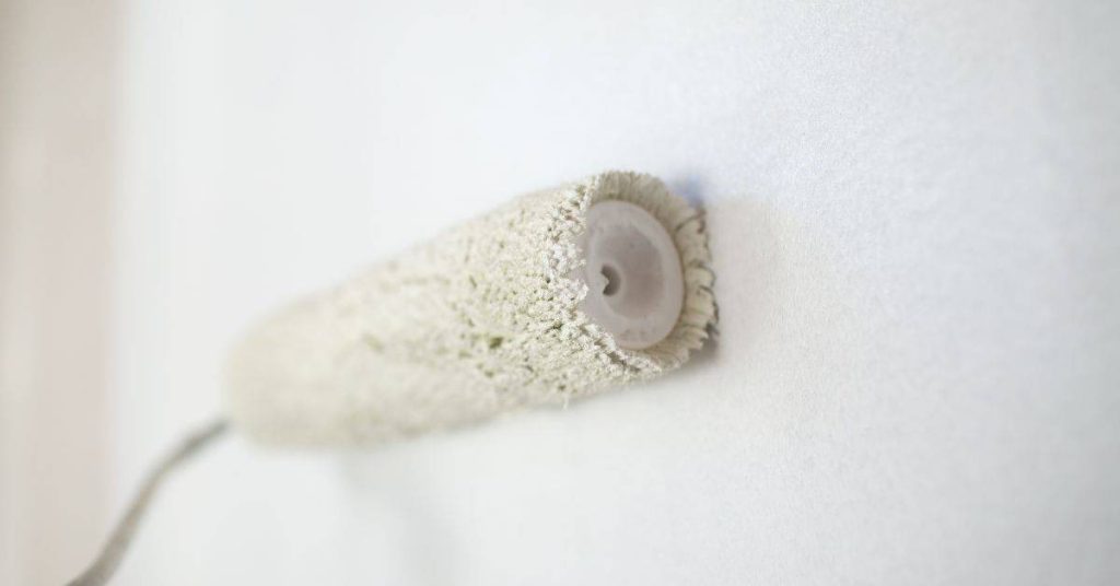 Close-up of a paint roller against a white wall surface