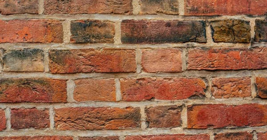 close-up of weathered red brick wall with mortar joints