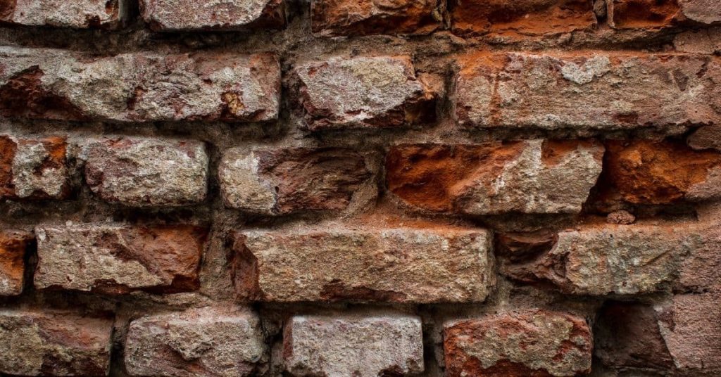 Close-up of weathered red brick wall with white deposits