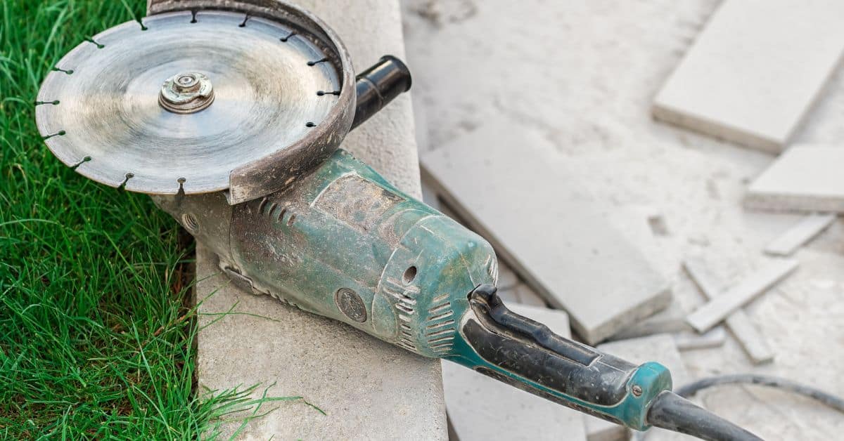 Angle grinder tool resting on concrete edge with debris